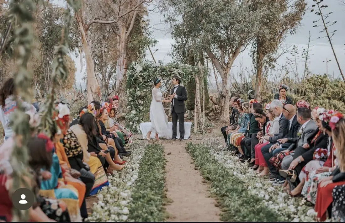 Outdoor wedding ceremony aisle lined with white flowers